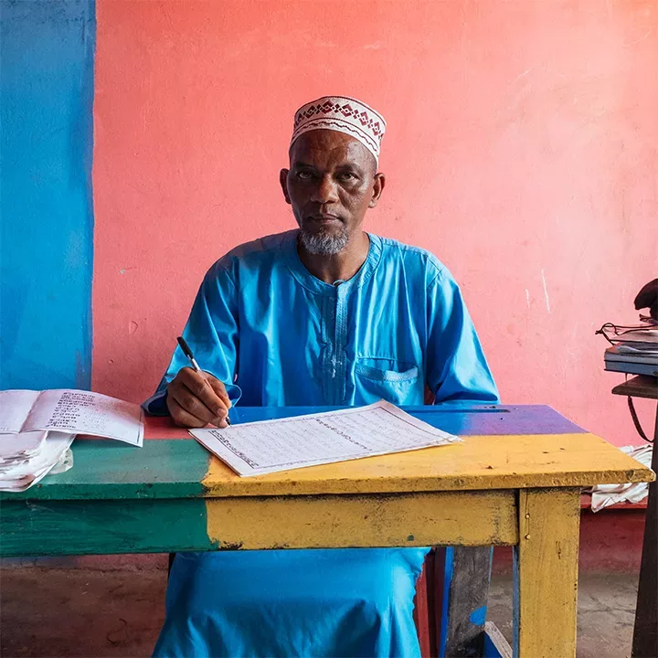 person at desk with papers containing ADLaM writing