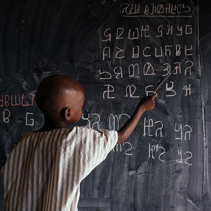 Child at chalkboard learning ADLaM
