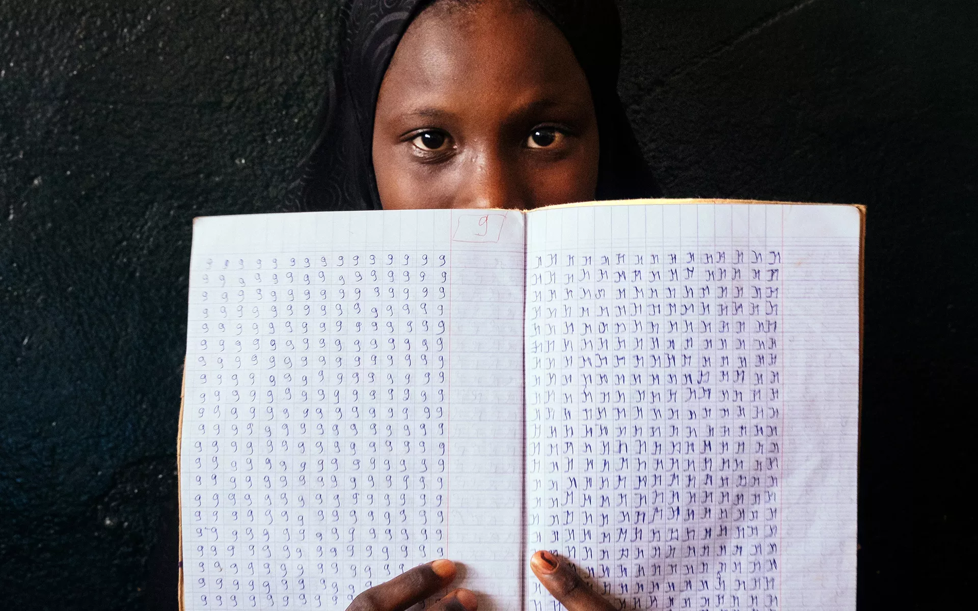 person holding notebook with ADLaM writing
