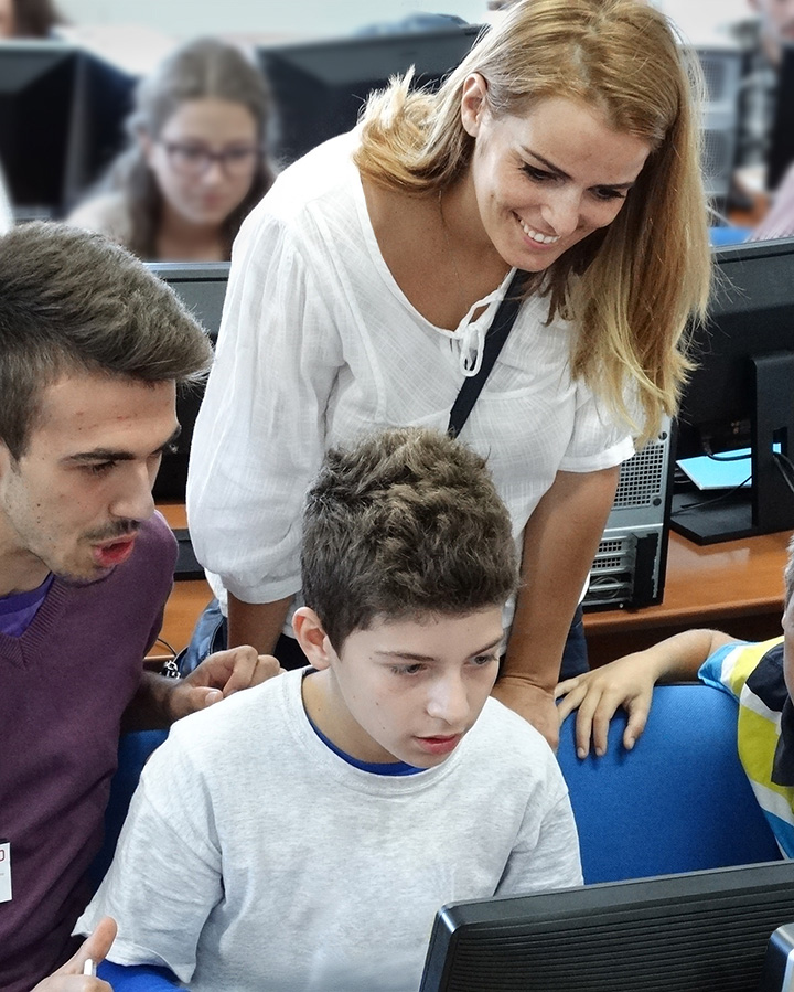 child at computer with adults looking on