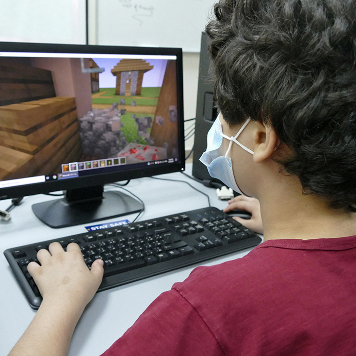 child at computer with Minecraft on screen