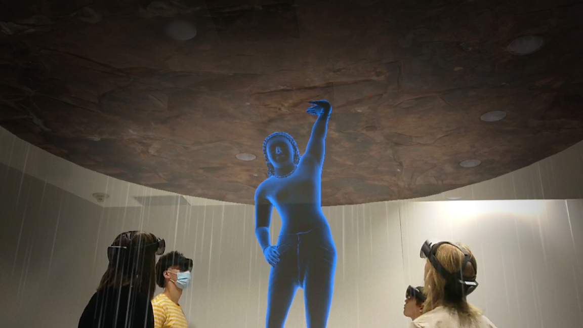 people viewing a blue hologram of the sandstone sculpture of Krishna fifting Mount Govardhan