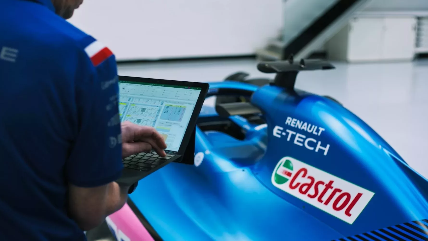 An engineer points to data on a Microsoft Surface tablet in the BWT Alpine F1 Team garage.