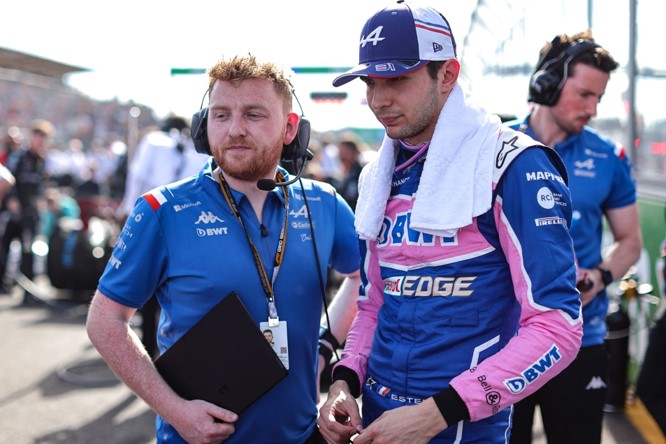 Esteban Ocon stands next to a BWT Alpine F1 Team engineer who is holding a Microsoft Surface tablet on the F1 track.