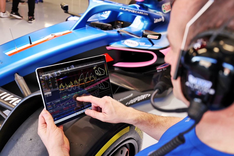 An engineer points to data on a Microsoft Surface tablet in the BWT Alpine F1 Team garage.
