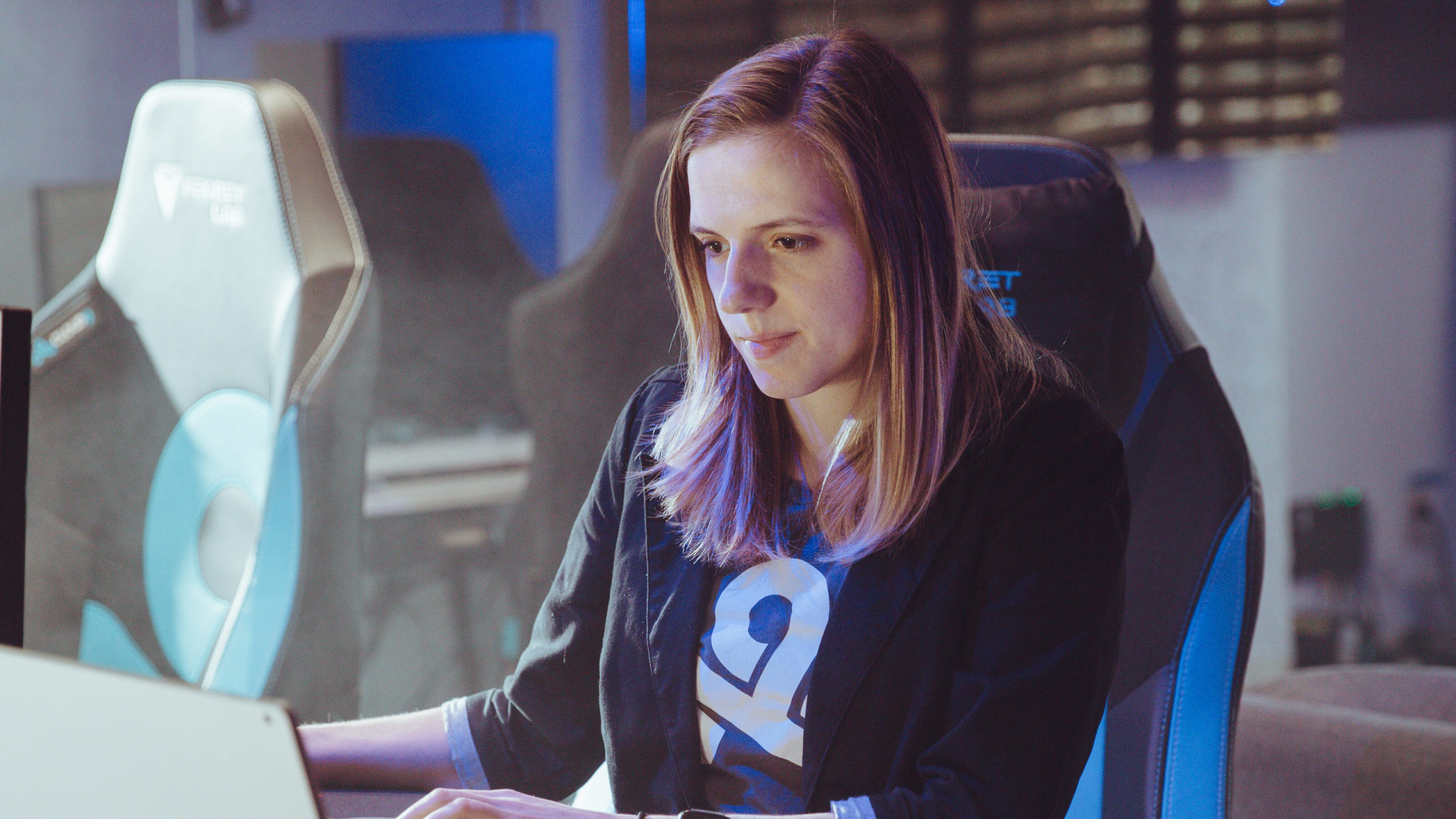 A woman works on her laptop in an empty workspace.