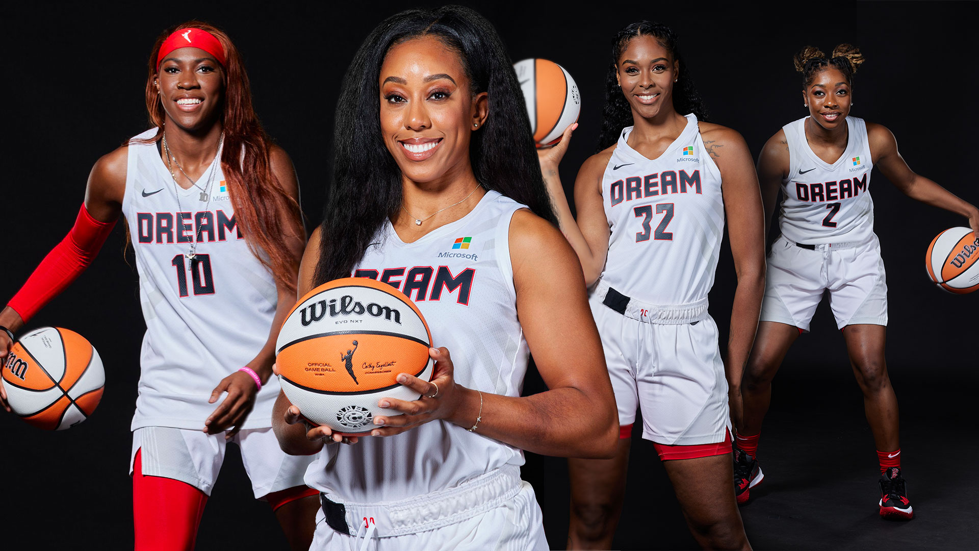 Four players from the Atlanta Dream basketball team stand in their jerseys with basketballs in their hands.