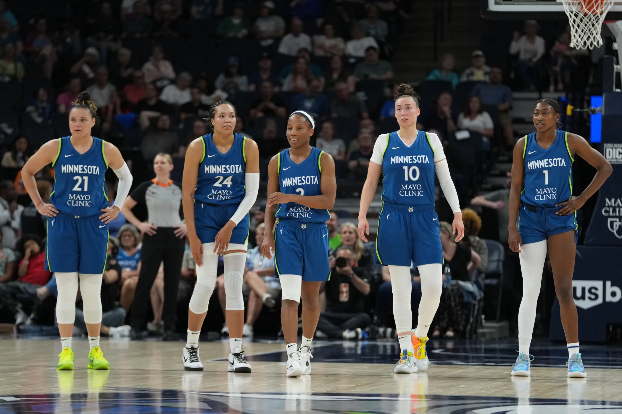 Minnesota Lynx basketball players in dark blue uniforms walk next to each other on a basketball court.