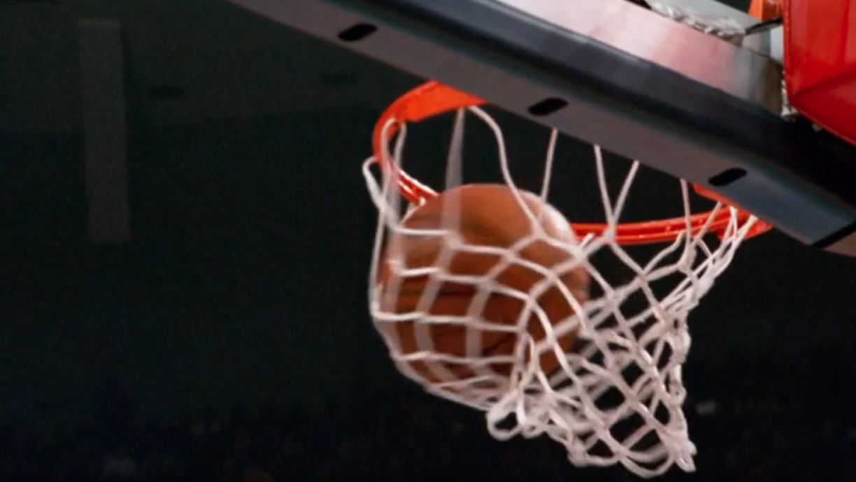 A basketball swishes through a net at an NBA game.