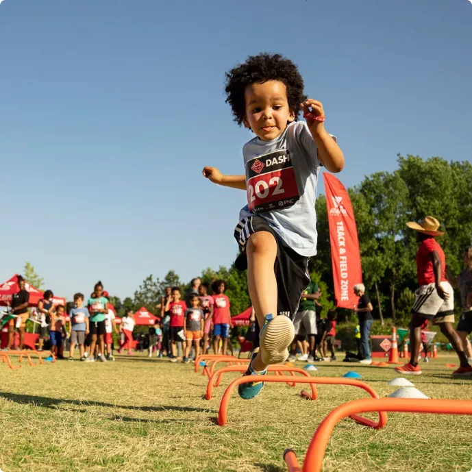 A young boy jumping over obstacles in a park.