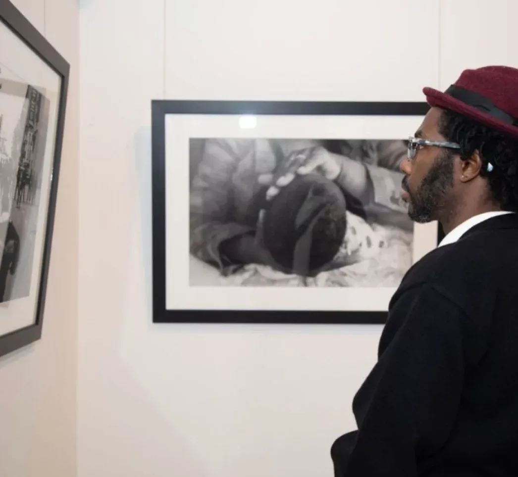 Three men gathered around a laptop smiling at the camera with art hanging in the background