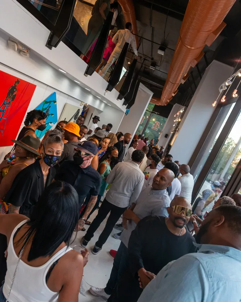 Bird’s-eye view of a group of people standing in an art gallery with framed art hanging on white walls