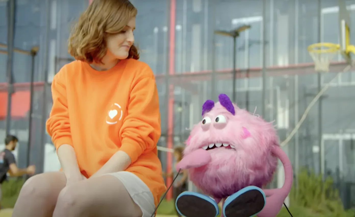 Woman in orange shirt talking with Pink Feelings Monster