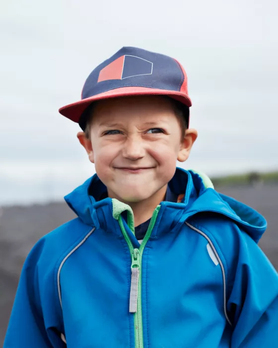Portrait of a young boy in a blue jacket and navy baseball cap