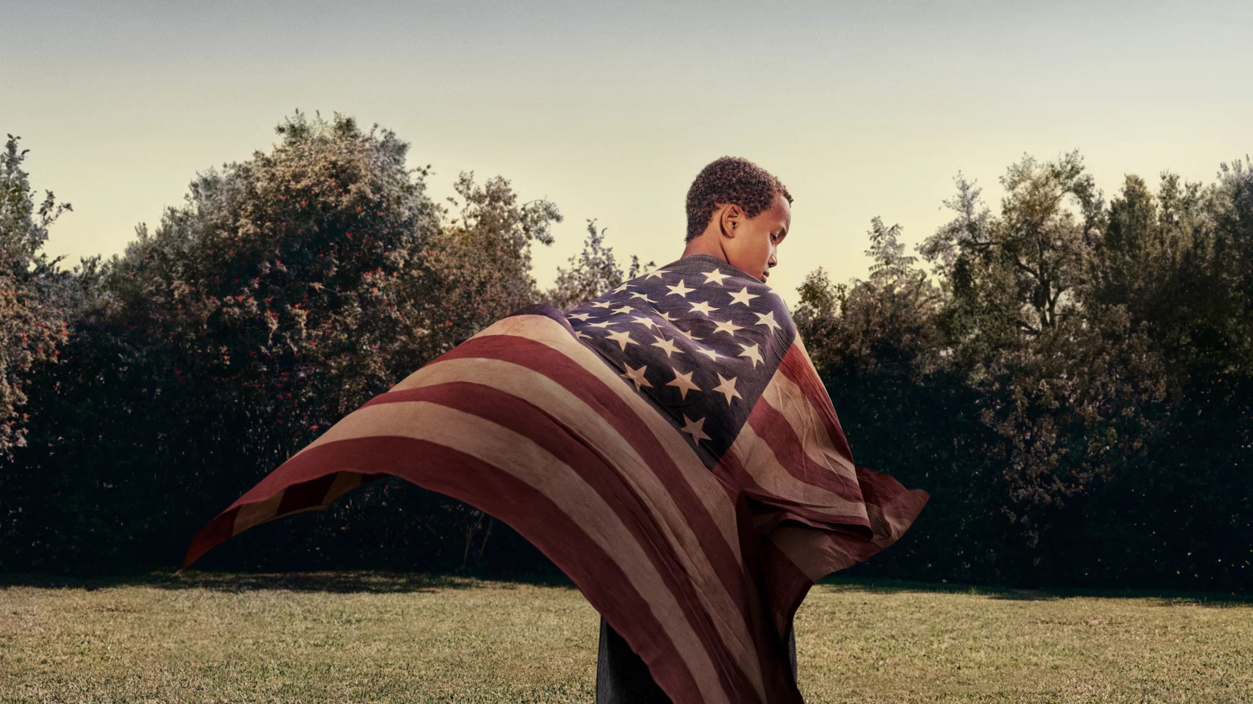 Young, African-American boy wrapped in the flag of the United States of America