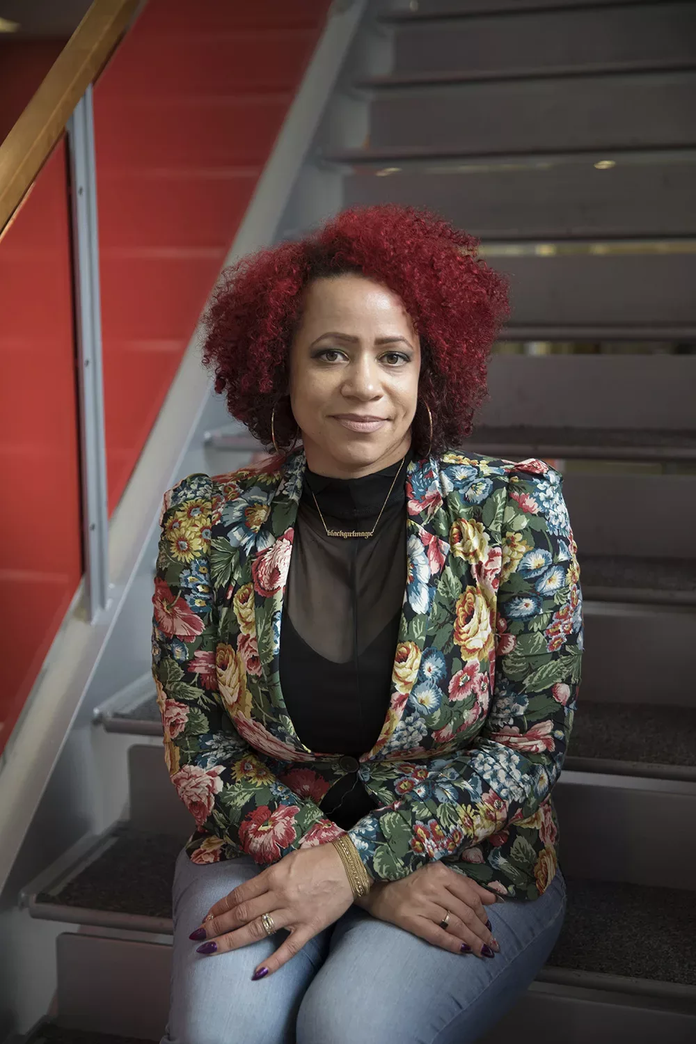 Nikole Hannah-Jones in a floral jacket sitting on a flight of stairs