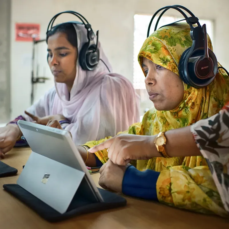 Women in bangladesh using a laptop with headphones.