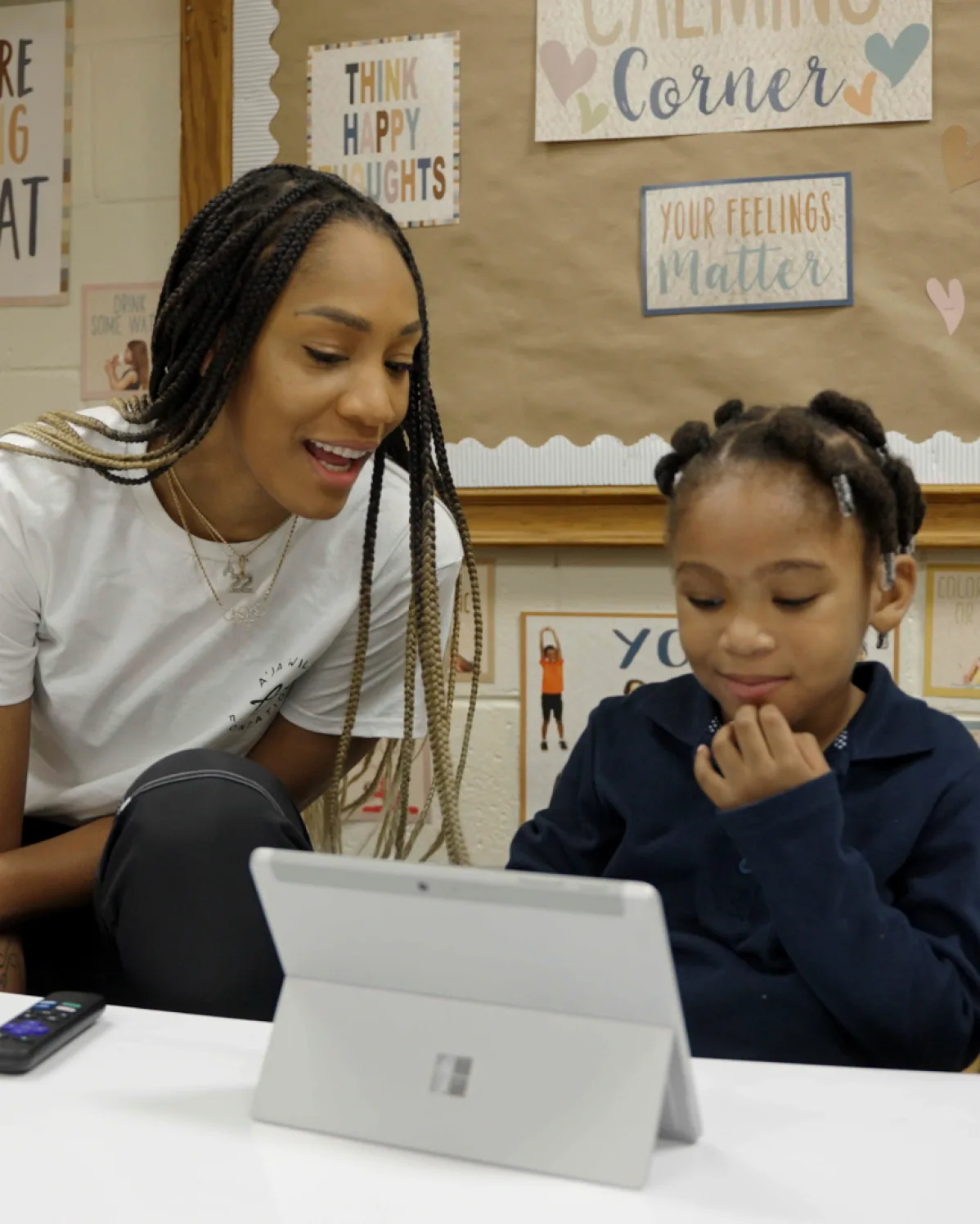 A’ja Wilson watches a young girl use a Microsoft Surface device in a classroom.
