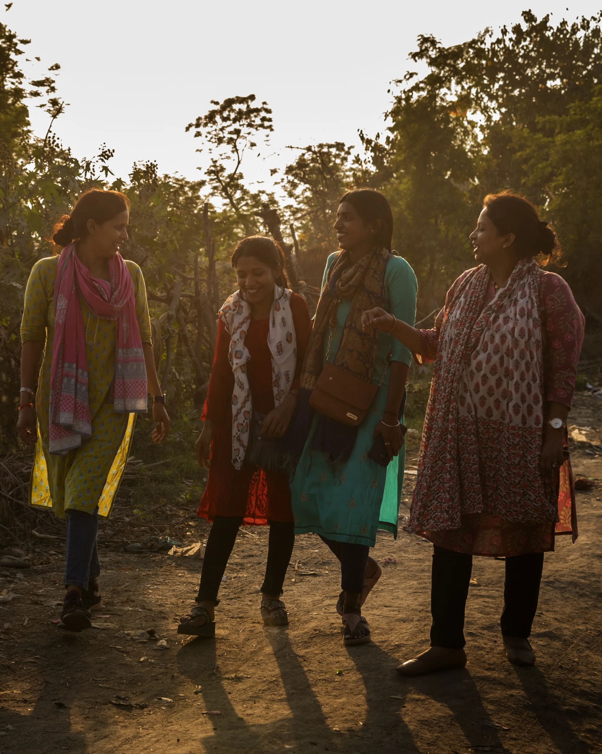 A group of women walk together outside talking and smiling.