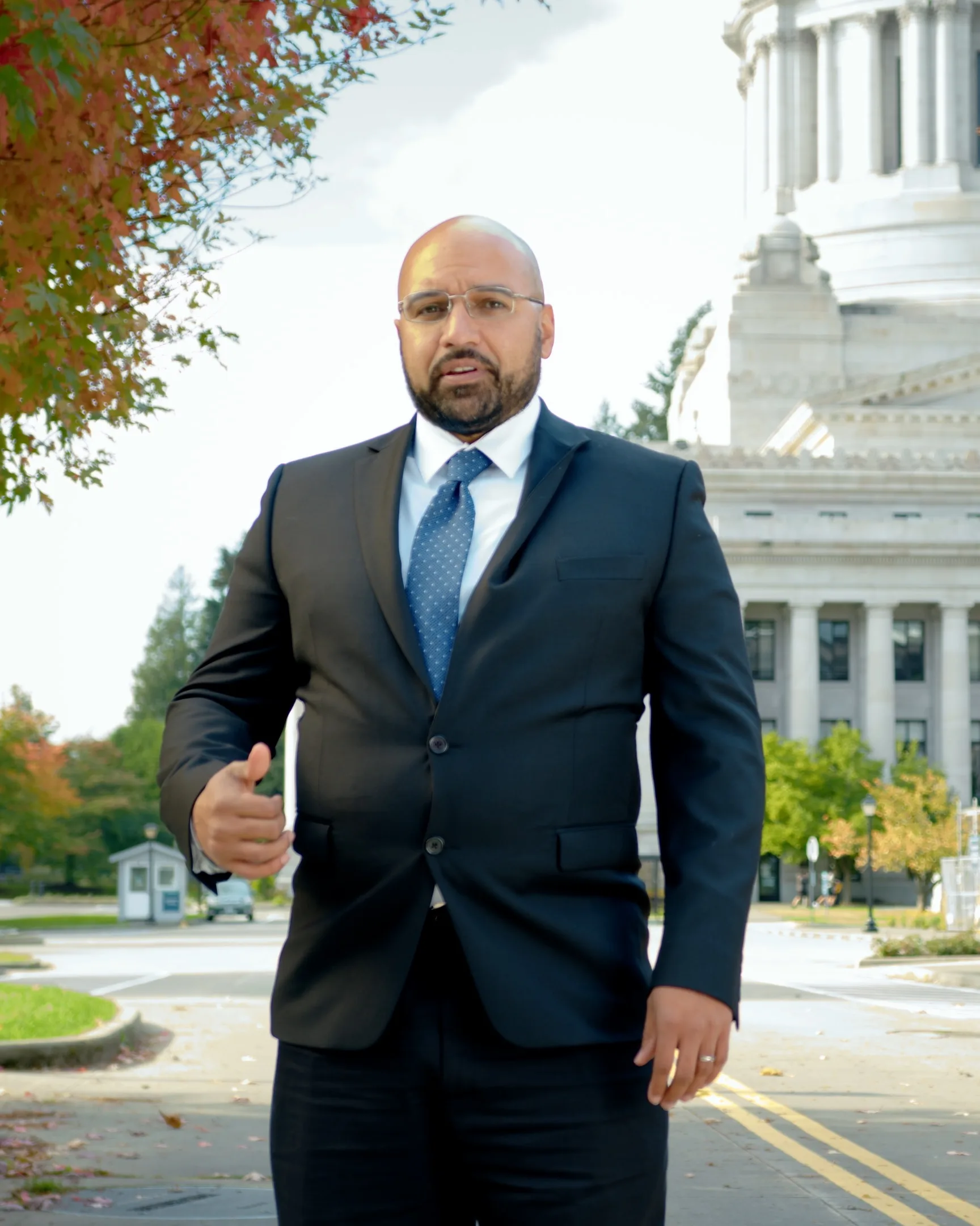 A portrait of Anthony Powers in a suit standing outside.