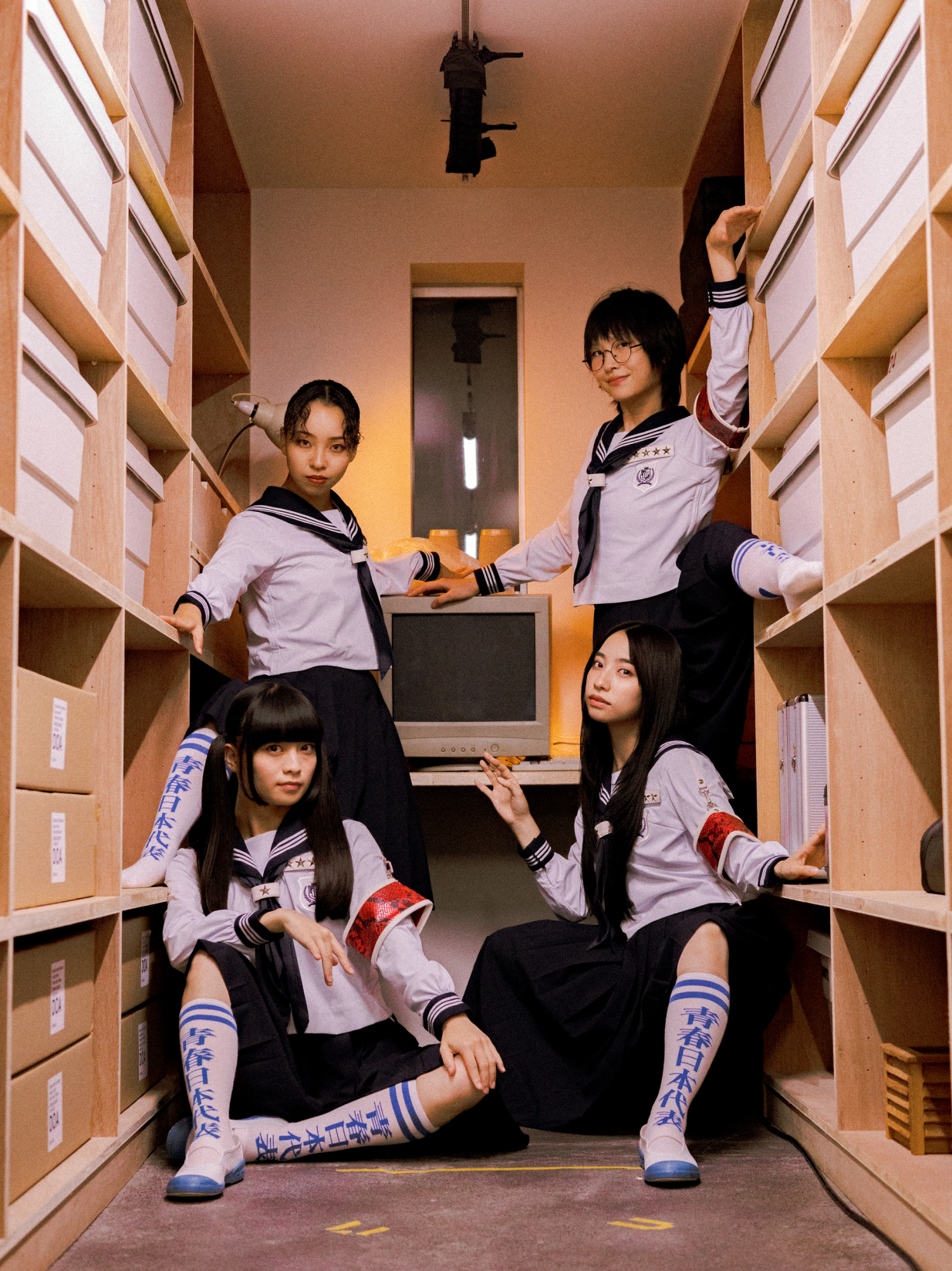 Four asian girls posing in a room full of bookshelves.