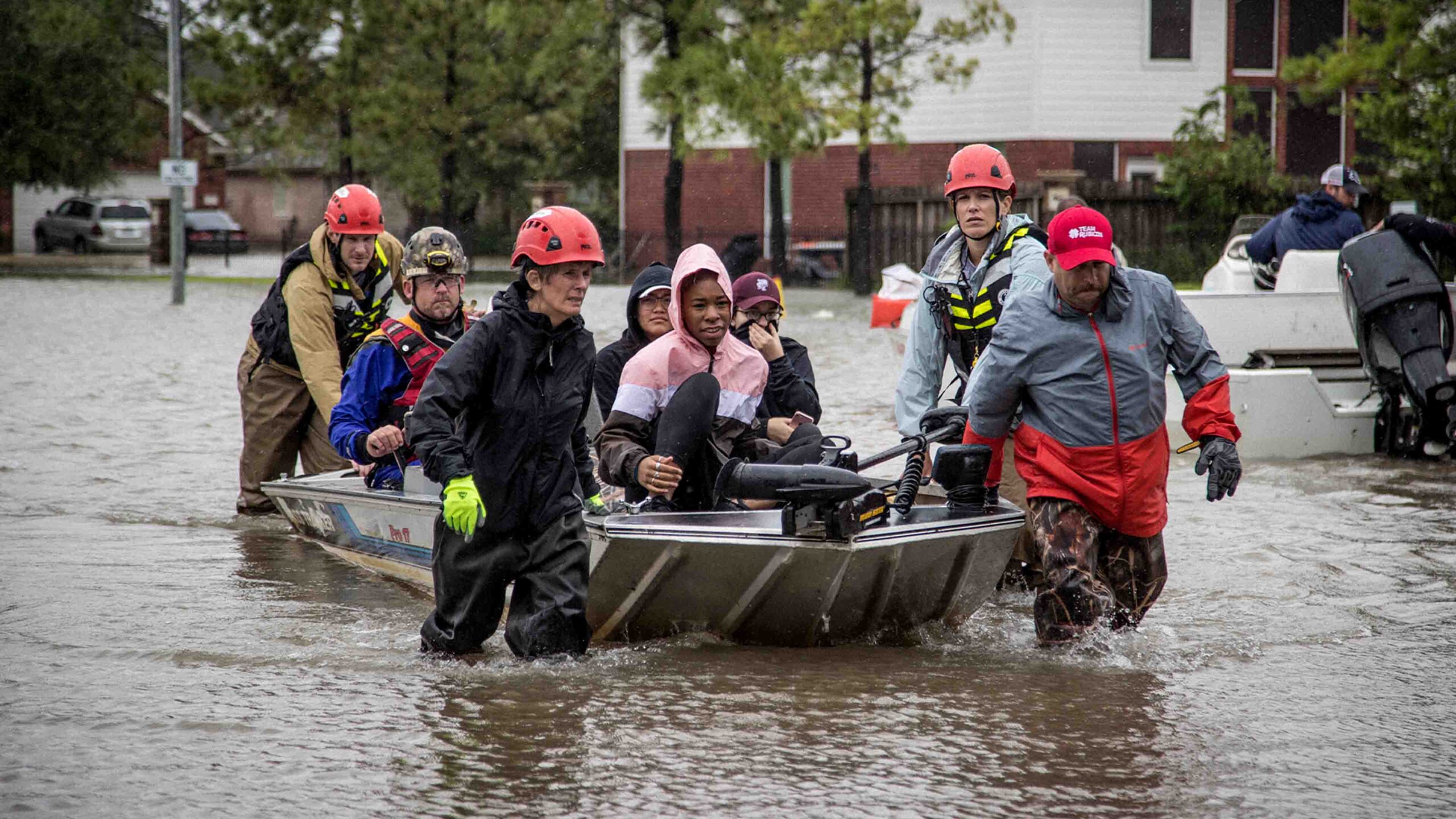 A group of people riding in a boat on a flooded street.