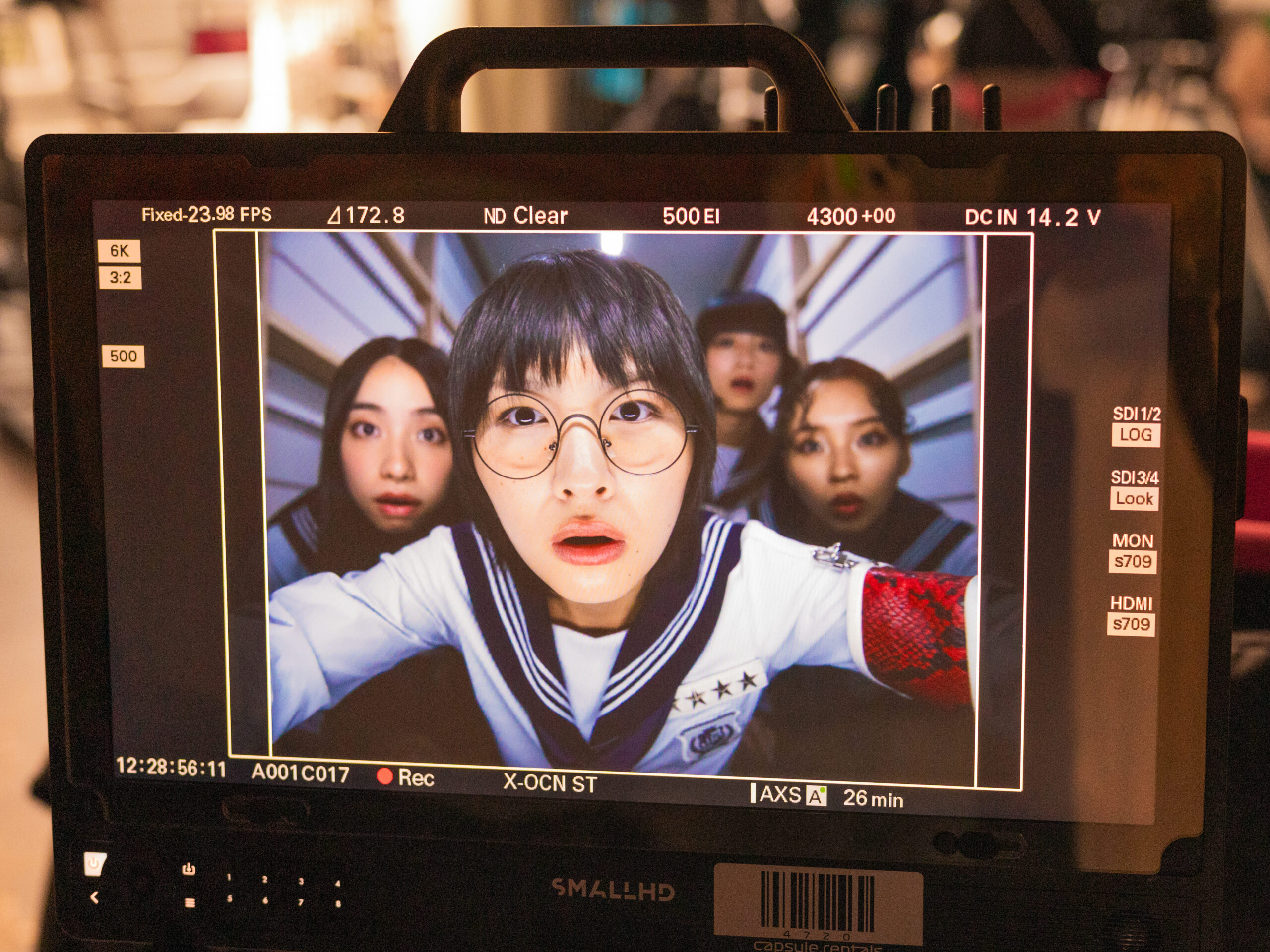 A group of girls looking shocked, displayed on a tv screen.