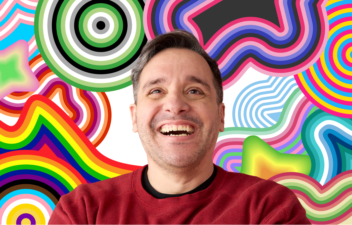 A person smiles widely in front of a colorful background featuring various abstract and wavy patterns. They are wearing a red sweatshirt.