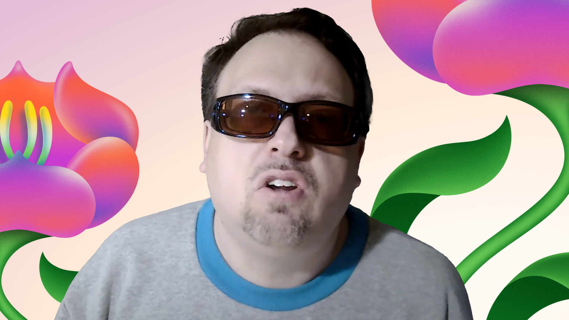 A man wearing sunglasses speaks against a colorful background with abstract floral designs.