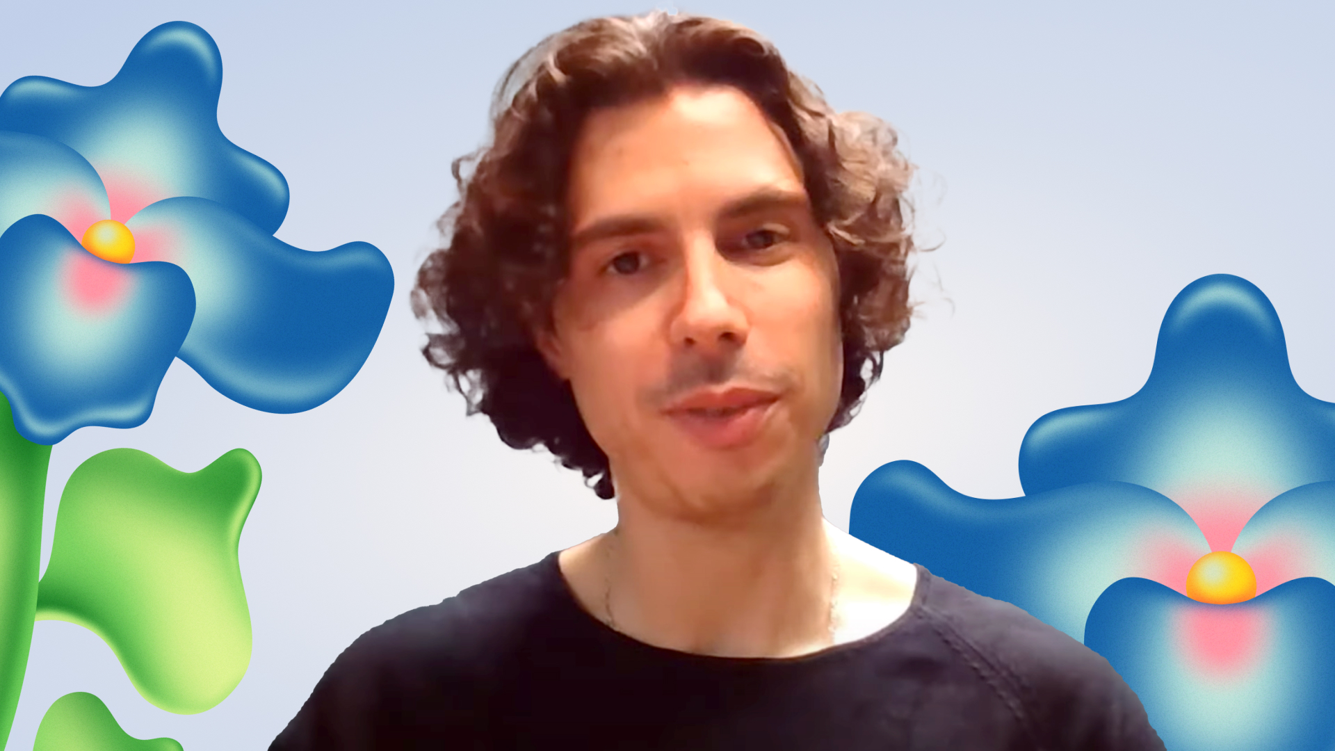 A man with curly hair in a black shirt standing in front of a background with abstract blue and green flowers.