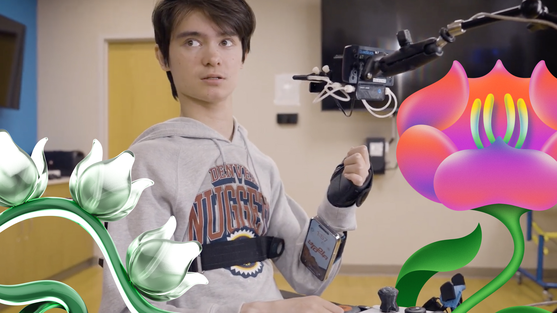 A young man in a wheelchair operates a device with his mouth, wearing a denver nuggets hoodie, surrounded by stylized animated flowers.