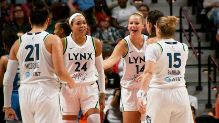 Female basketball players from the minnesota lynx team celebrating during a game, with jerseys displaying team name and sponsor logos.