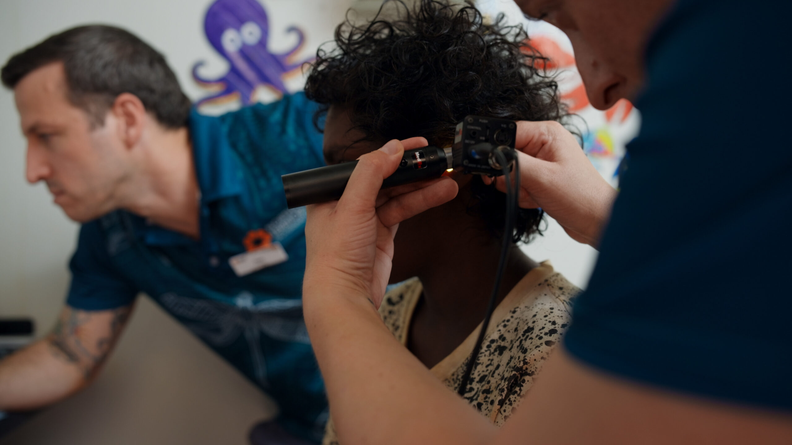 A person is having their ear examined with an otoscope by a healthcare professional in a clinic setting.