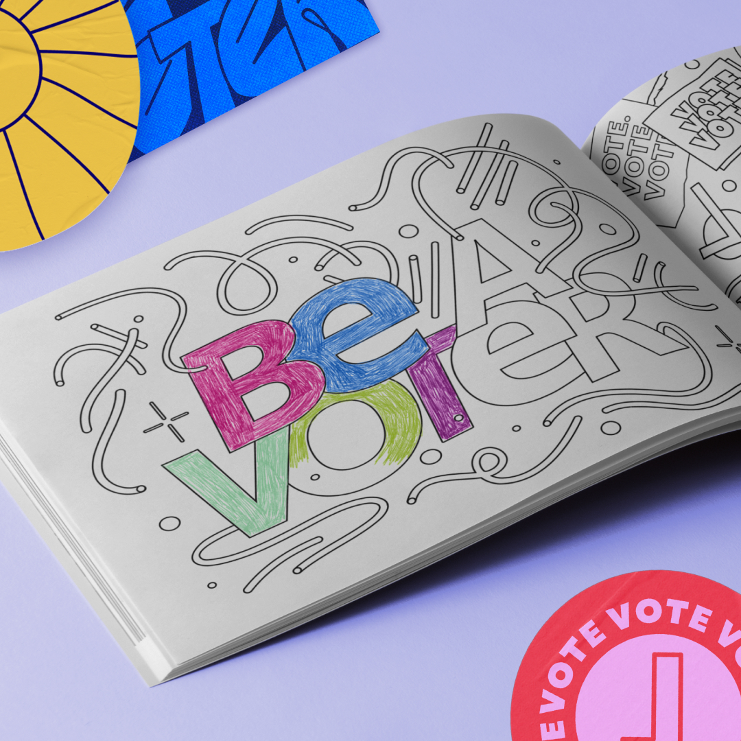 A coloring book open to a page with "Be a Voter" partially colored in blue, purple, yellow, and green. Nearby are circular "Vote" stickers and a sun illustration.