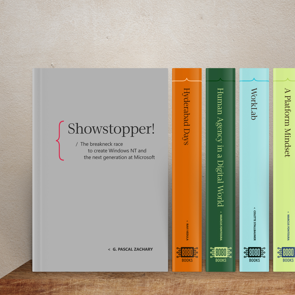 Five books stand upright against a beige wall. The prominent gray book is titled Showstopper! by G. Pascal Zachary. Four colorful books stand to its right with titles on their spines, each labeled “BOOKS 8000.”.