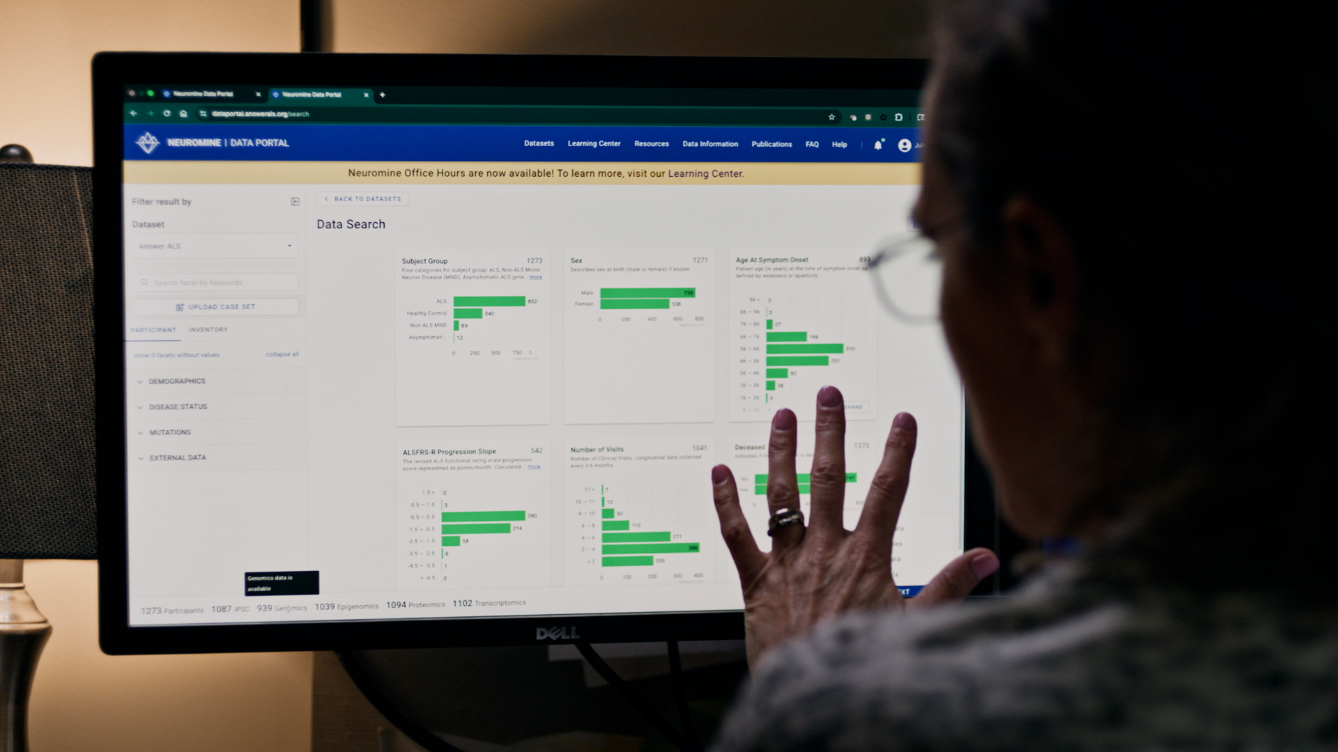 Person pointing at a computer monitor displaying Neuromine Data Portal with interactive medical data charts and graphs