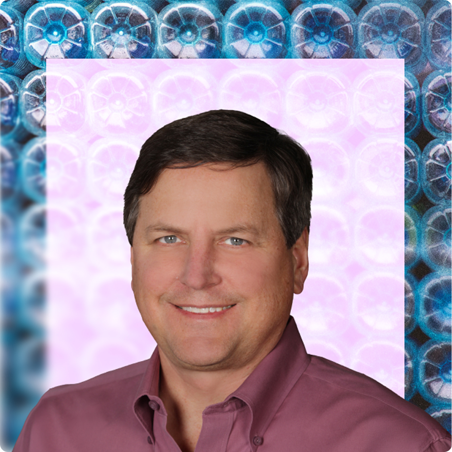 A middle-aged man with dark hair and blue eyes, wearing a mauve button-up shirt, smiling in a professional headshot framed by a border of blue plastic water bottle bottoms.